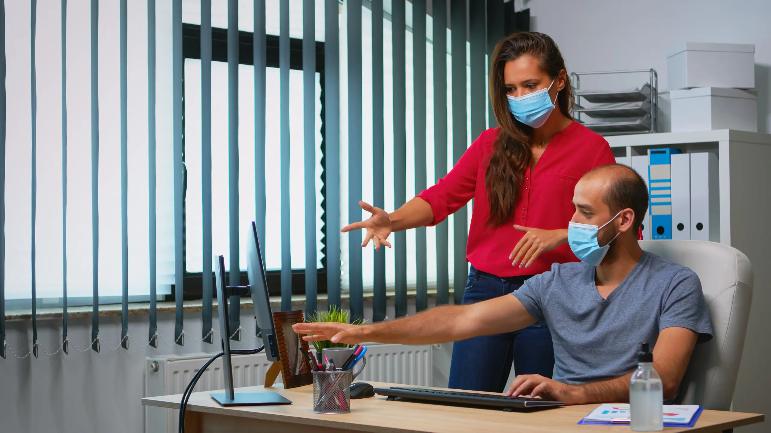 workers-talking-wearing-protection-face-masks-office-room-coronavirus-team-new-normal-office-workspace-personal-corporate-company-typing-computer-keyboard-pointing-desktop